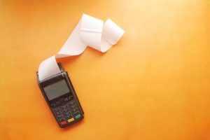 Payment terminal machine with large blank receipt coming out of it