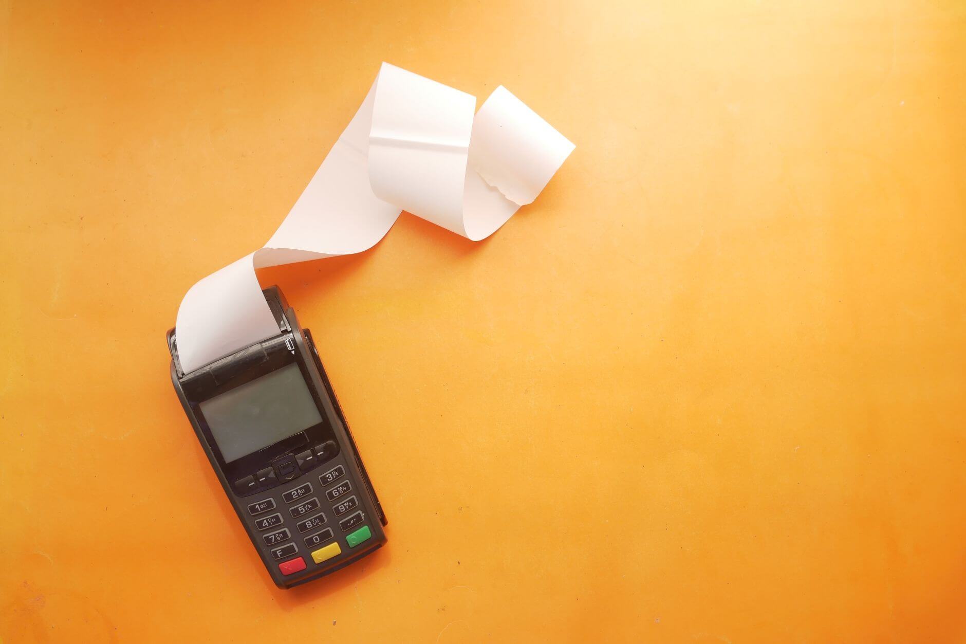 Payment terminal machine with large blank receipt coming out of it