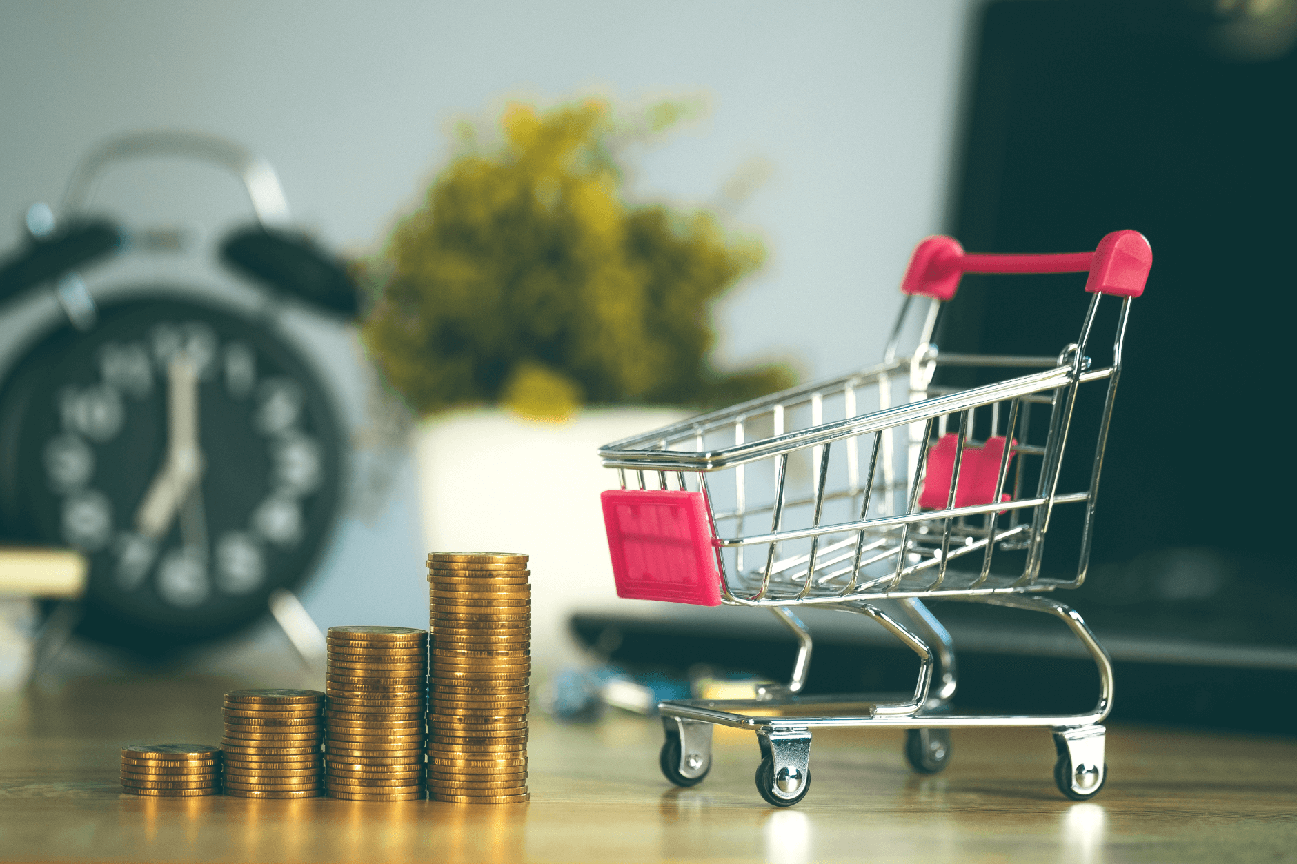 Miniature shopping cart and stacks on coins on a table