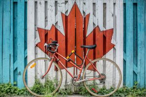 a bicycle leaning on a fence painted with Canadian flag